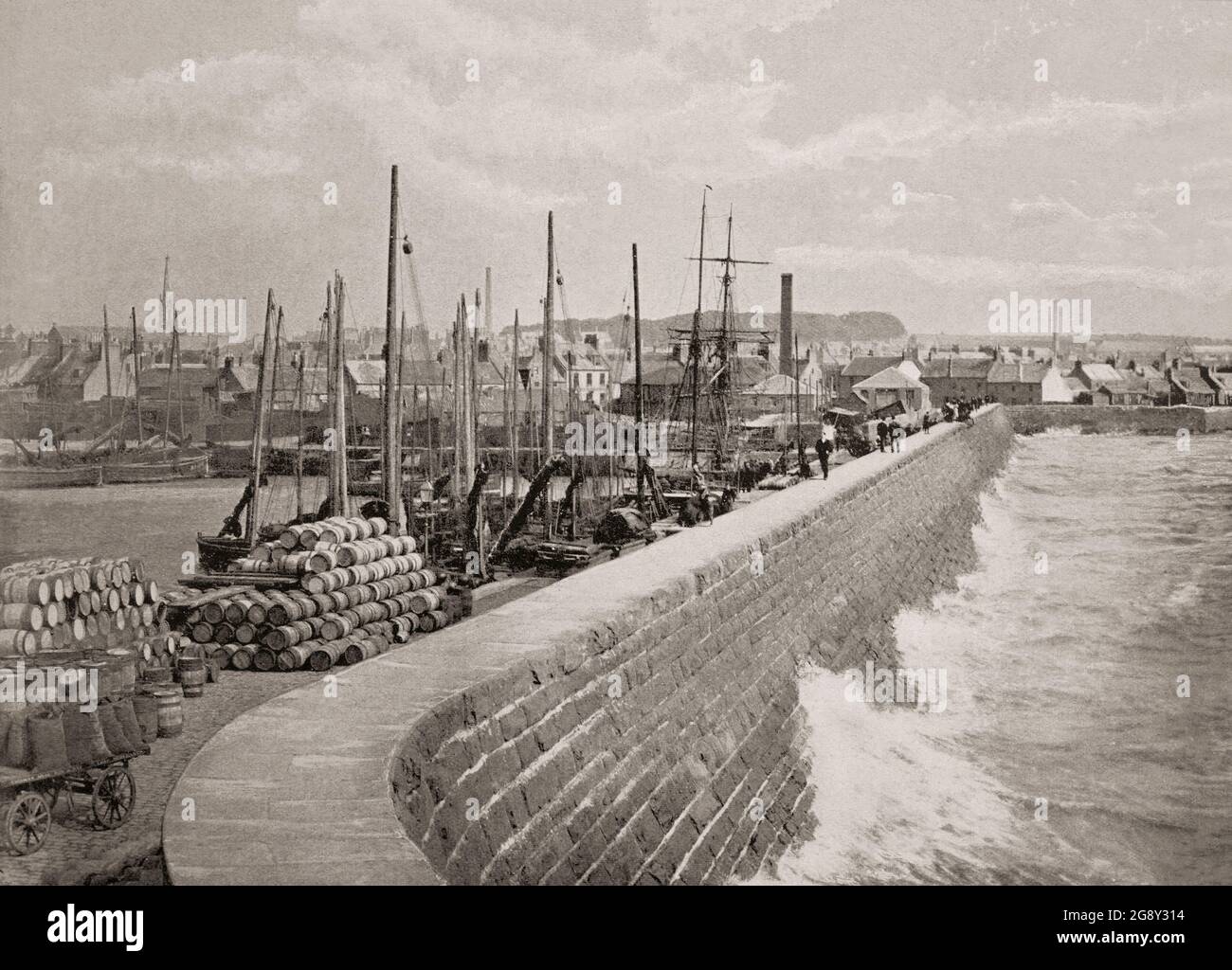 A late 19th century view of the harbour wall at Arbroath, a former royal burgh and the largest town in the council area of Angus, Scotland. The new harbour created in 1839 and by the 20th century, Arbroath was one of Scotland's larger fishing ports. It is notable for the Declaration of Arbroath and the Arbroath smokie. Stock Photo