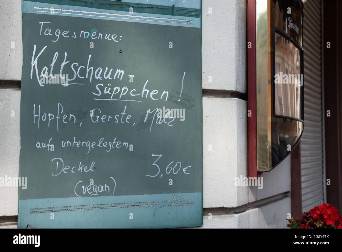 23 July 2021, Hessen, Frankfurt/Main: At a Frankfurt restaurant, a board advertises beer, humorously paraphrased as a menu of the day in the form of a 'cold foam soup' made of yeast, barley and malt on a lid placed underneath and therefore 'vegan'. Photo: Frank Rumpenhorst/dpa Stock Photo