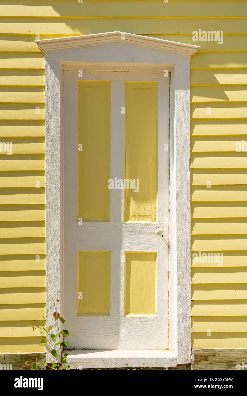 Old white and yellow door on the exterior of clapboard house Stock Photo
