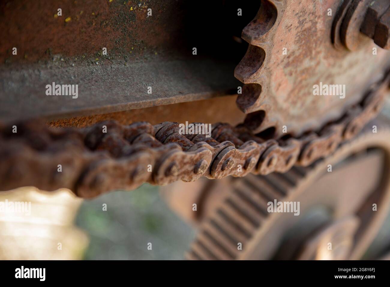 Rusty details of old abandoned cars. Gears, chains, pulleys rust in the open. Moss-covered metal parts of agricultural machinery. Stock Photo