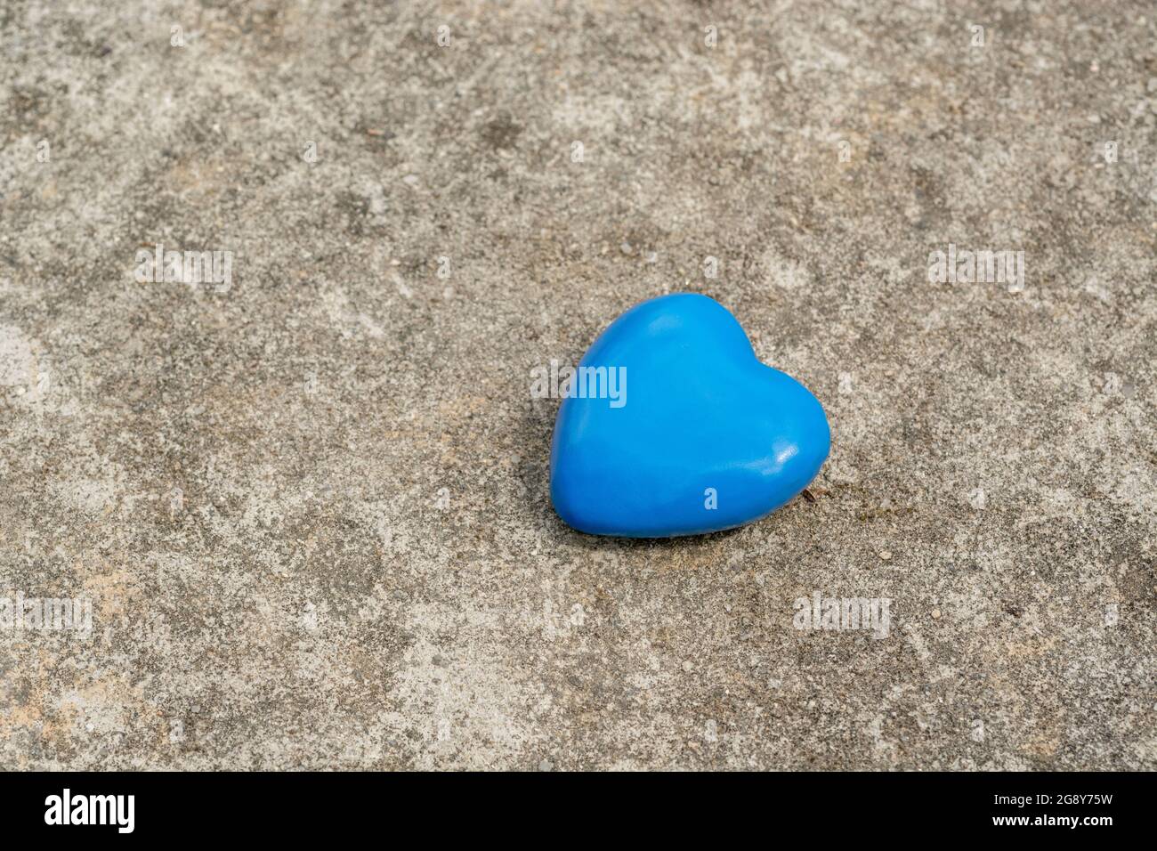 Blue heart on weathered cement surface for Blue Monday, feeling gloomy / dispirited, UK Covid lockdown mental health, career blues, being dumped. Stock Photo