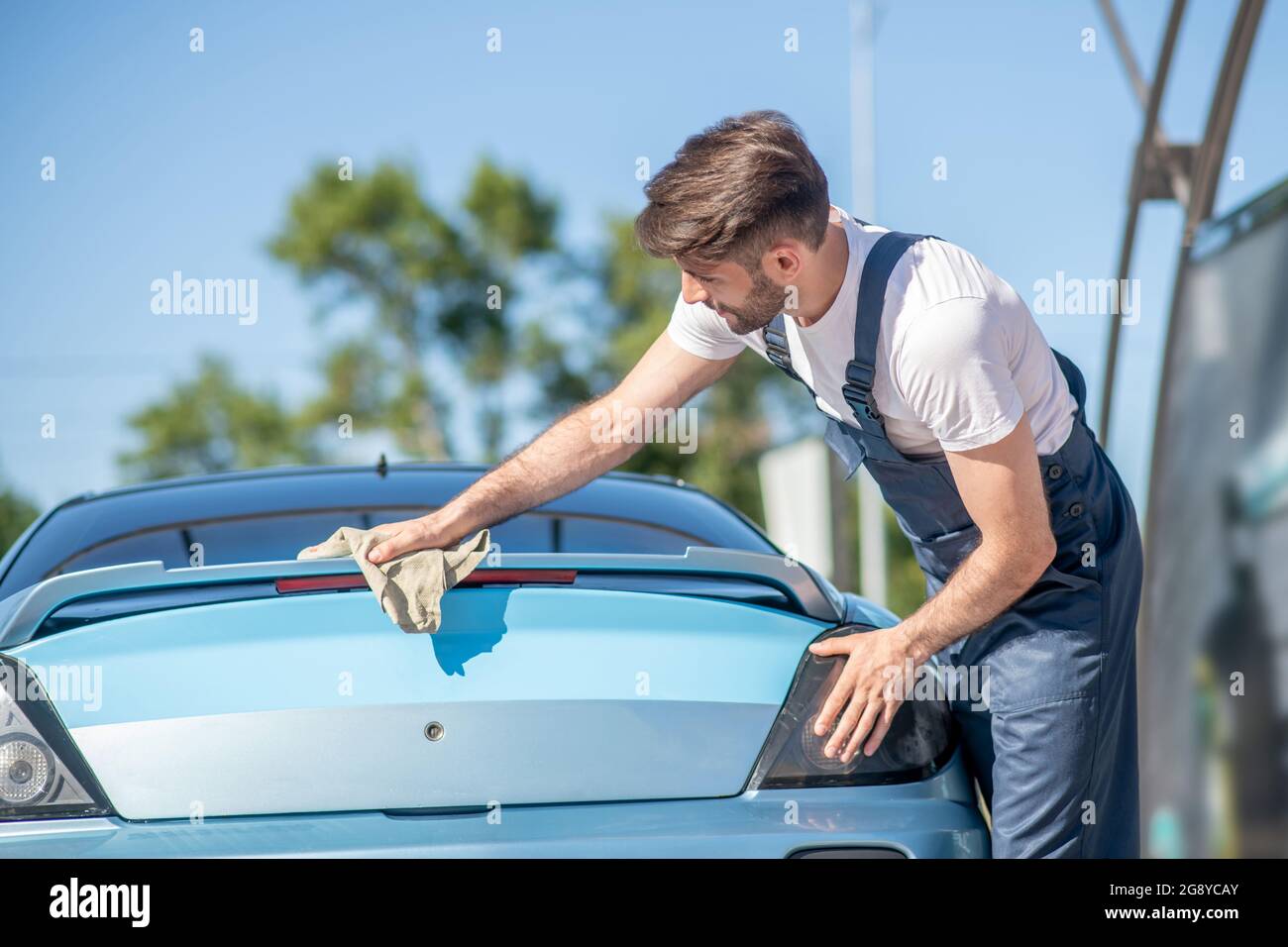 Man in overalls thoroughly wiping car Stock Photo