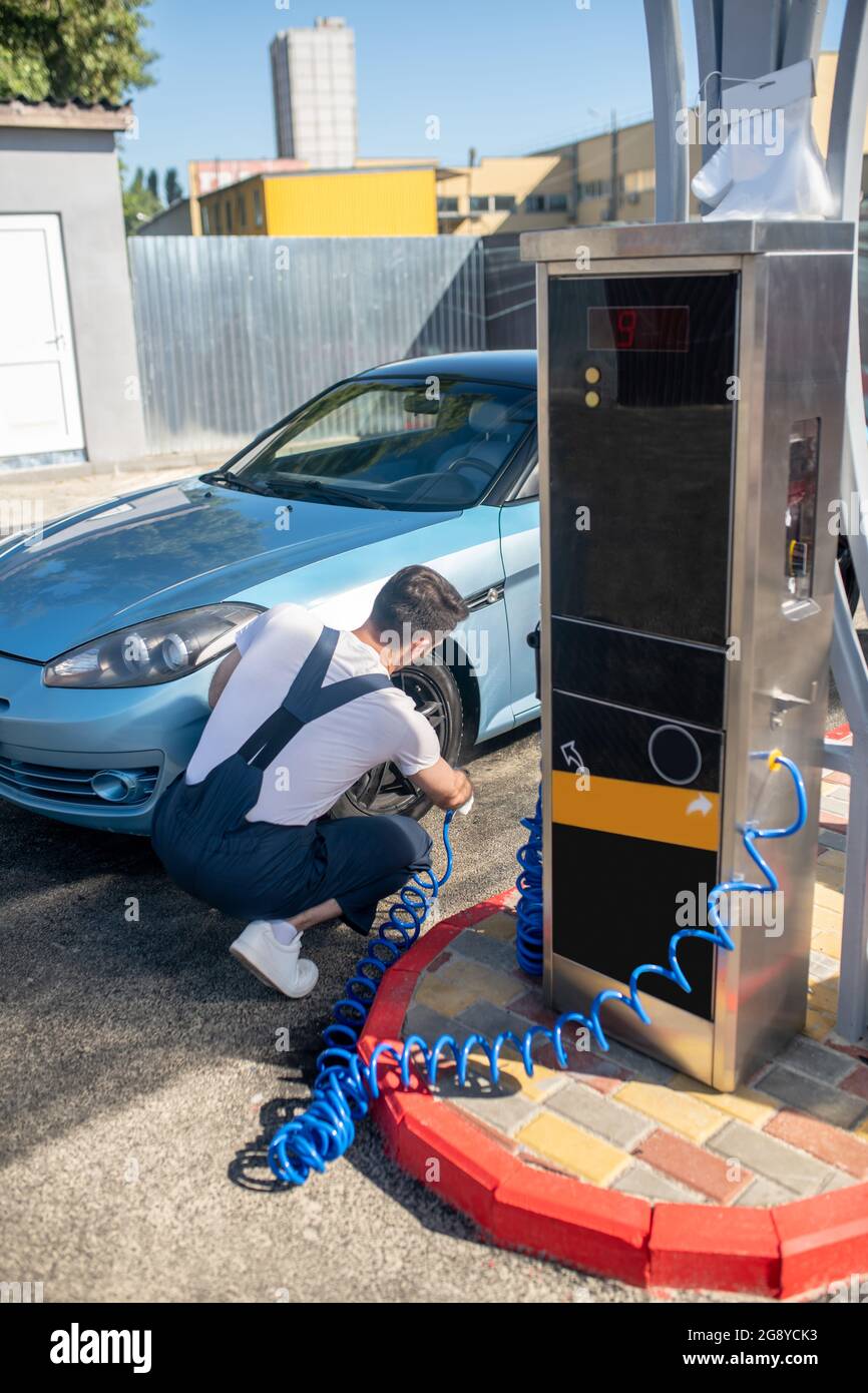 Man crouched near wheel of car with pump Stock Photo