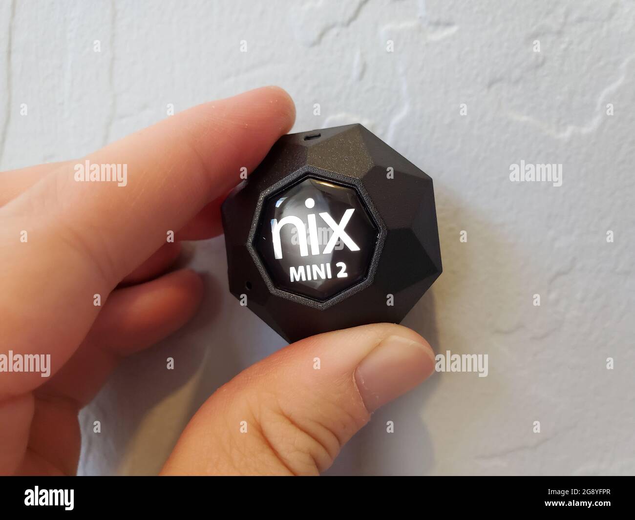 Closeup of human hand using Nix Mini 2 color sensor to determine paint