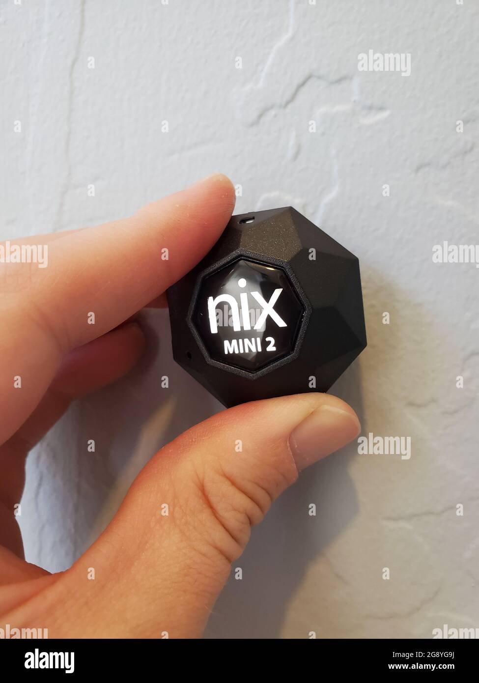 Closeup of human hand using Nix Mini 2 color sensor to determine paint