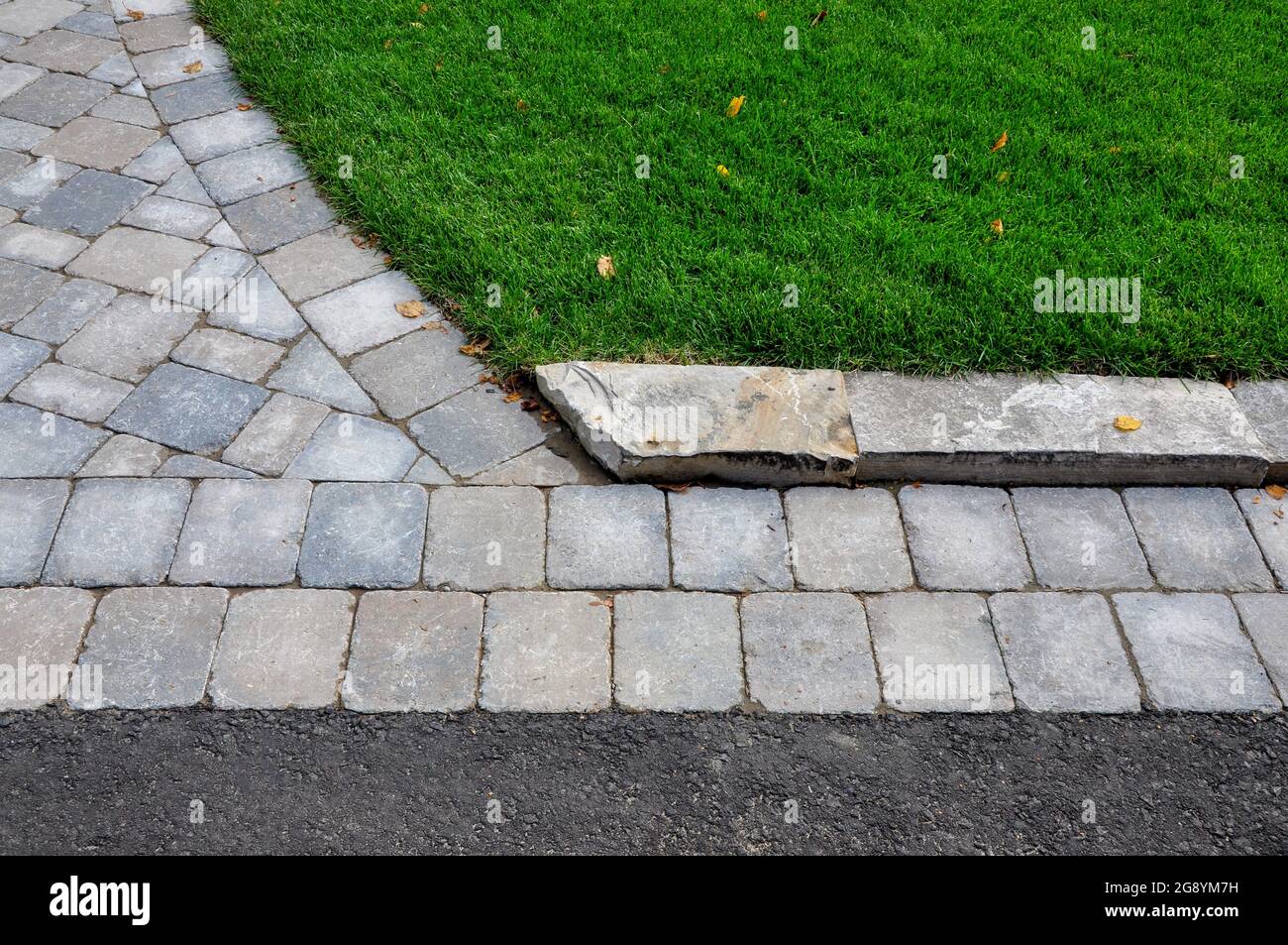This landscape project shows a professionally designed and crafted transition from walkway to driveway, and uses natural stone curbing. Stock Photo