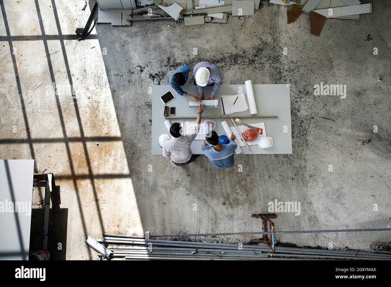 Four persons team of engineers talk together to review constuction material, taken from high angle, top view photo Stock Photo