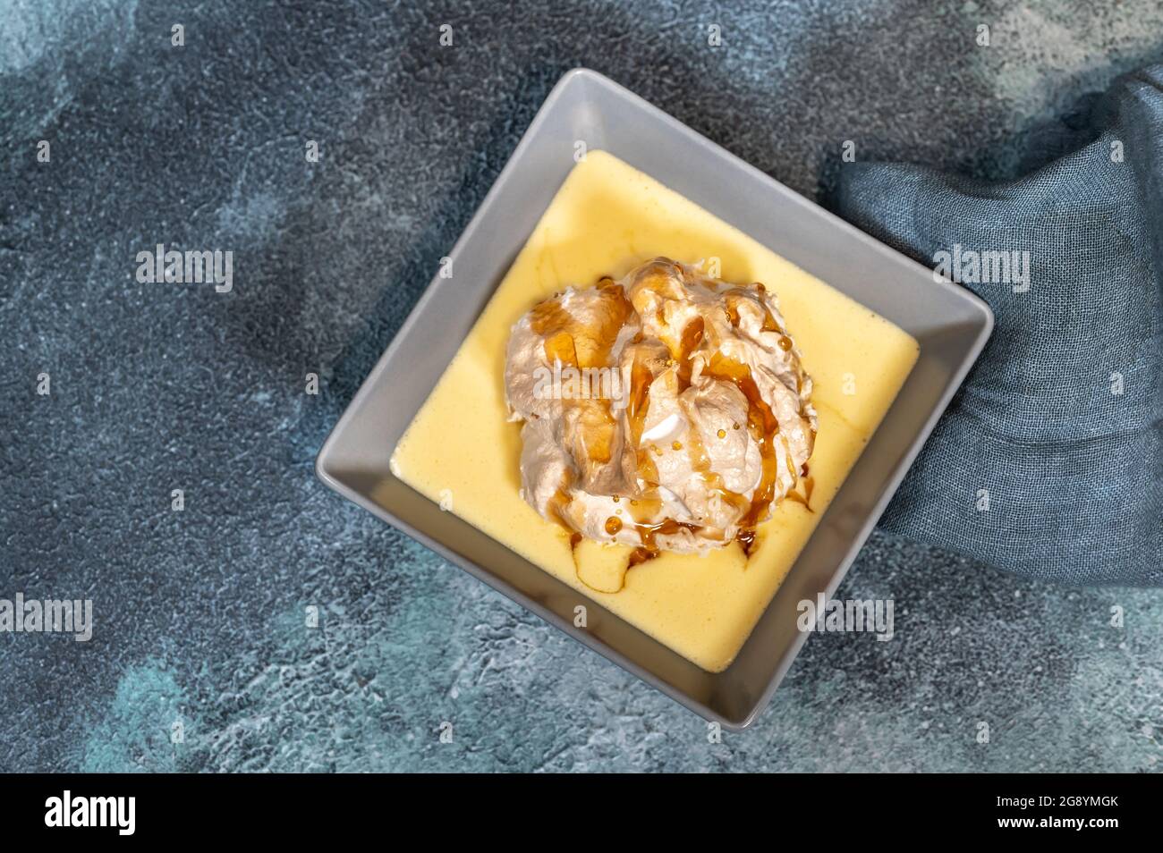 Floating island dessert made of meringue floating on vanilla custard