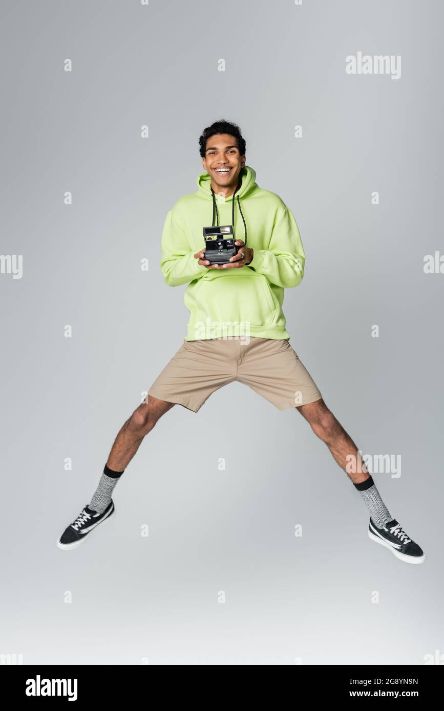 excited african american man levitating with vintage camera isolated on grey Stock Photo