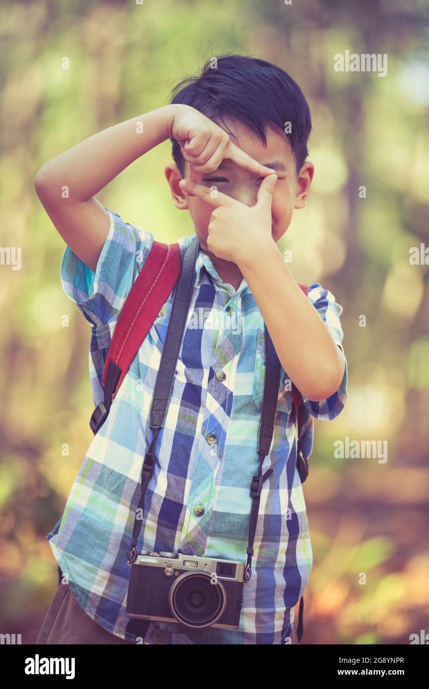 Asian boy with professional digital camera on blurred nature ...