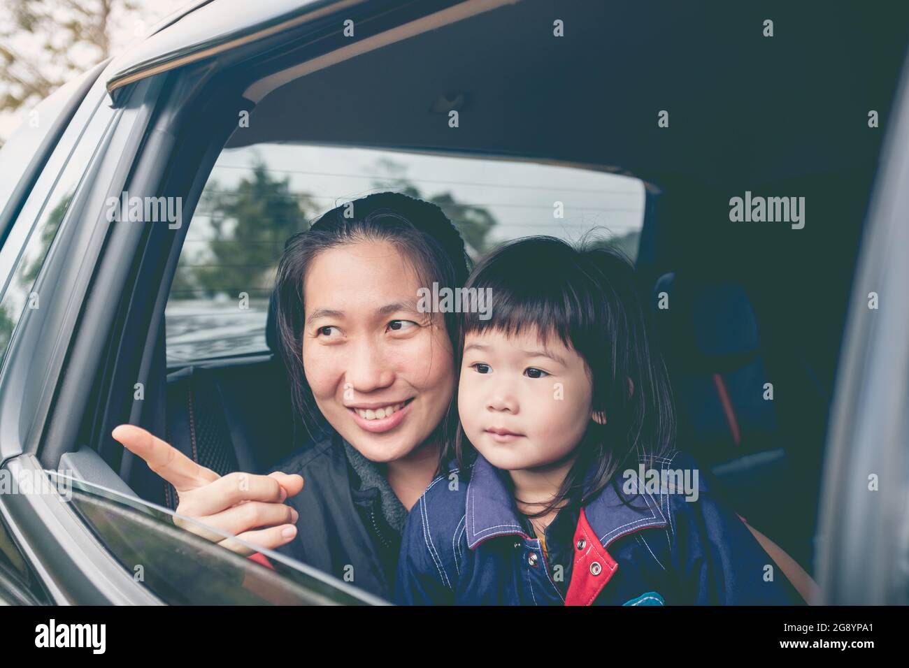 Family travelling by car. Asian mother and little lovely daughter travel on vacation. Happy parent and kid have fun. Outdoors. Stock Photo