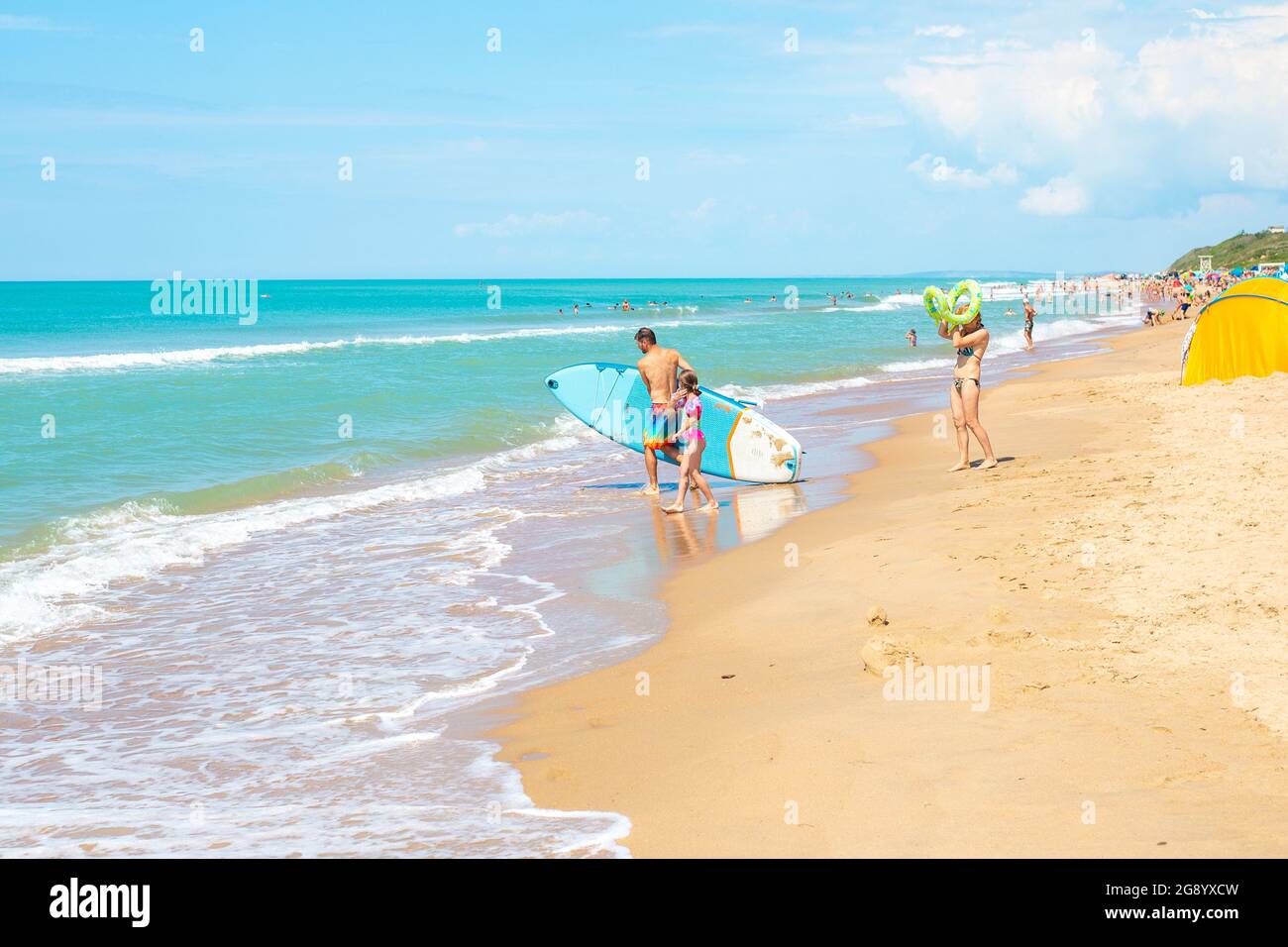 Anapa, Russia-07.07.2021: A man with a swimming board enters the sea. Entertainment and leisure at the seaside resort. Stock Photo