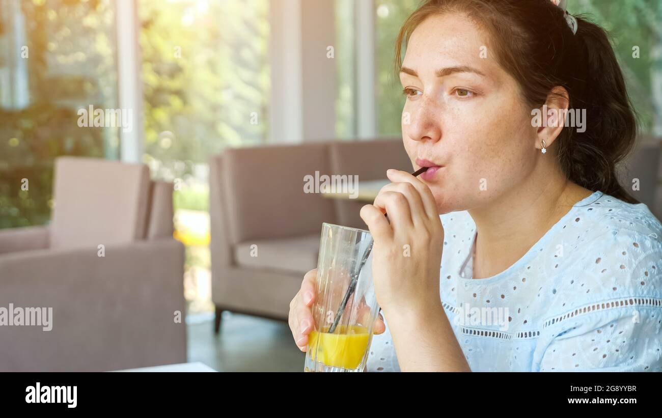 Attractive young lady drinks juice in cafe, side view Stock Photo