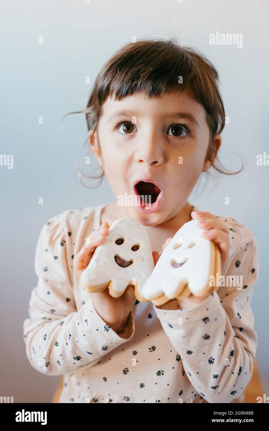 Cute girl with mouth open holding ghost cookies Stock Photo