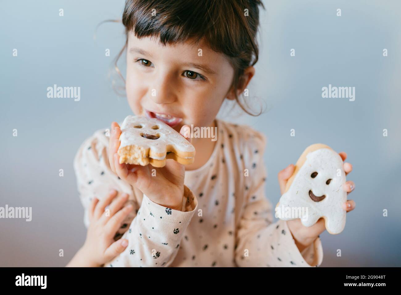 Little girl eating homemade halloween ghost cookies Stock Photo