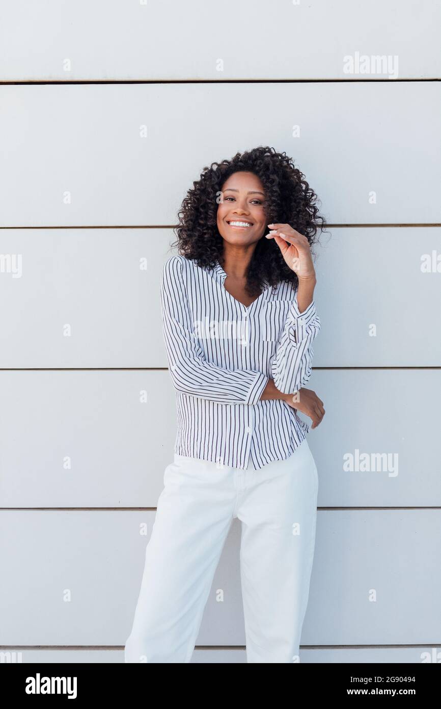 Happy young woman standing in front of wall Stock Photo - Alamy