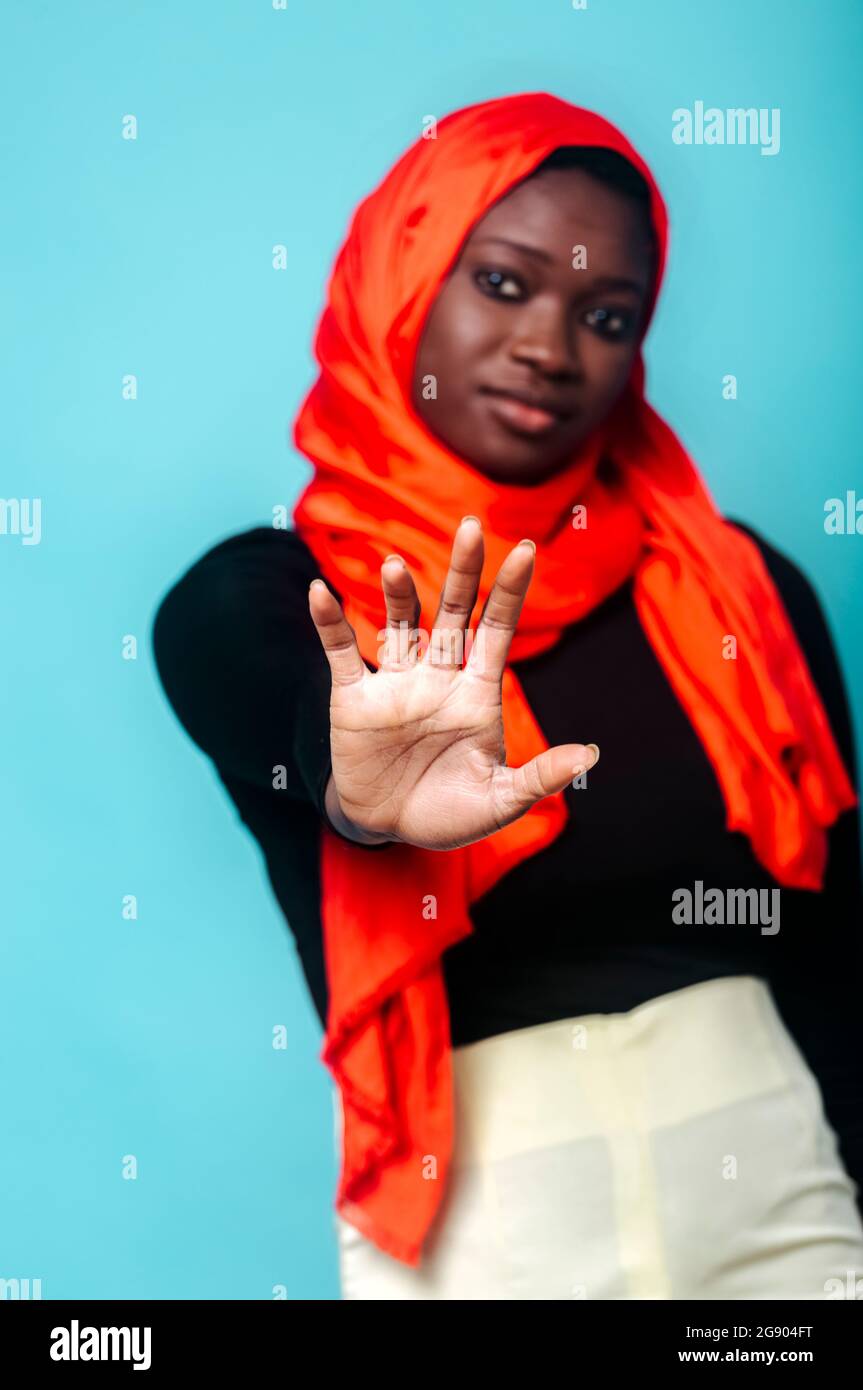 Young woman showing stop gesture in front of blue background Stock ...