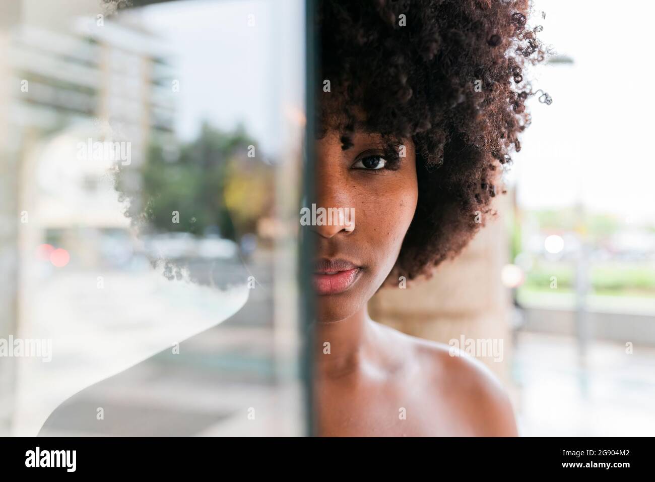 Young woman standing behind glass Stock Photo