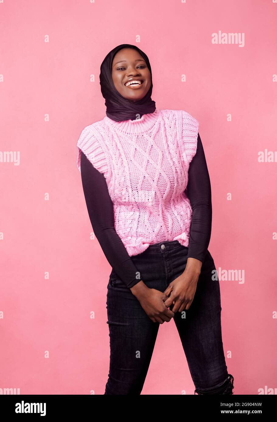 Smiling young woman standing in front of pink background Stock Photo ...