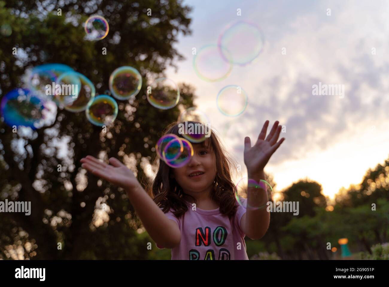 Girl playing with soap bubbles during sunset Stock Photo