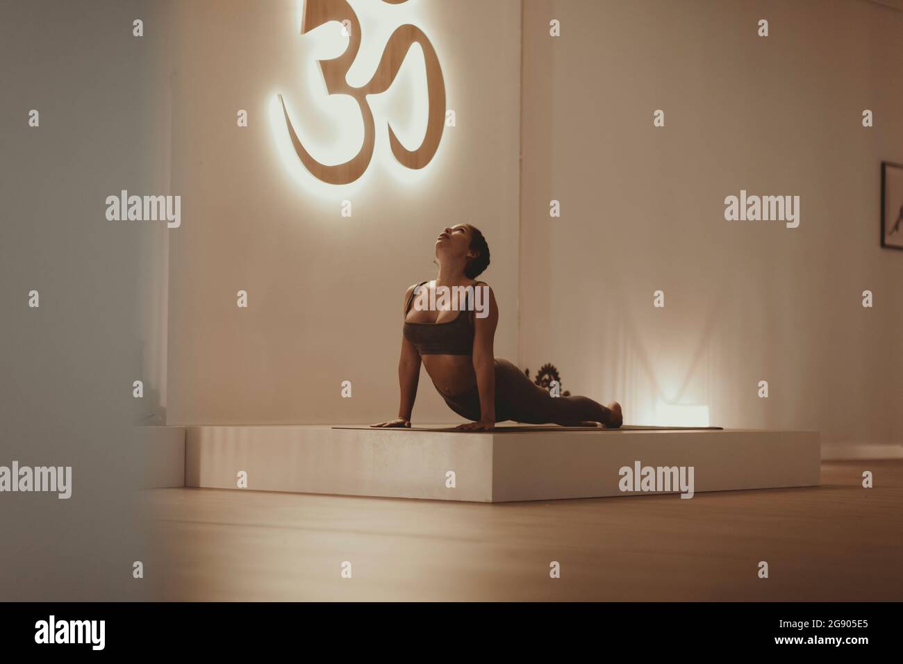 Female yoga instructor practicing sun salutation in yoga studio Stock Photo