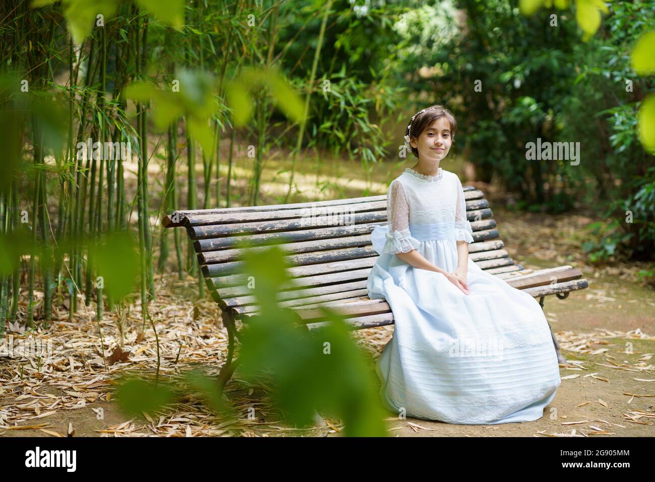 Smiling girl sitting in white dress on park bench Stock Photo - Alamy