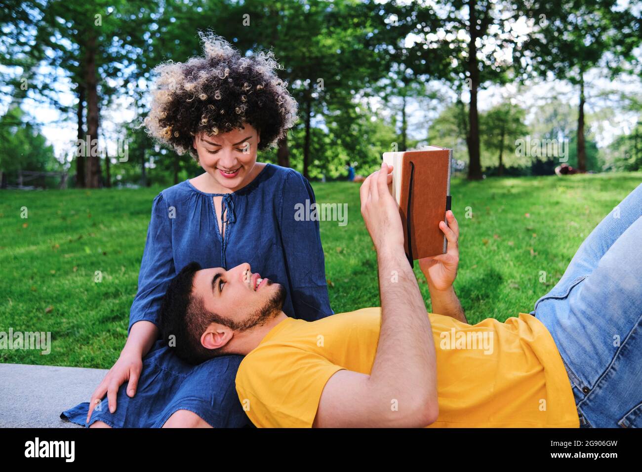 Smiling young woman looking at boyfriend lying on lap at park Stock Photo
