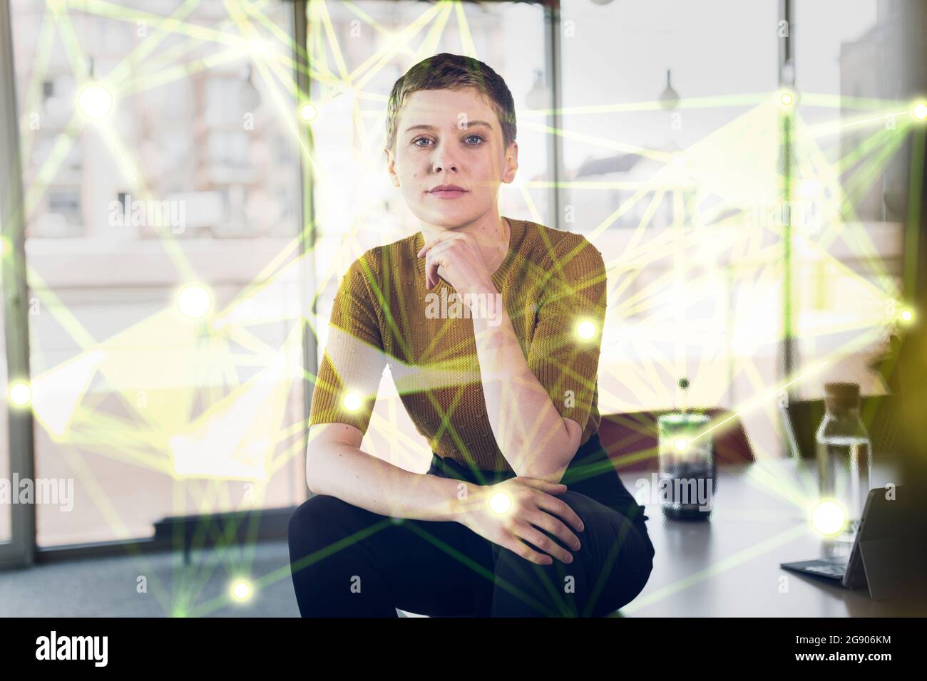 Female professional sitting on desk surrounded by global communication data at office Stock Photo