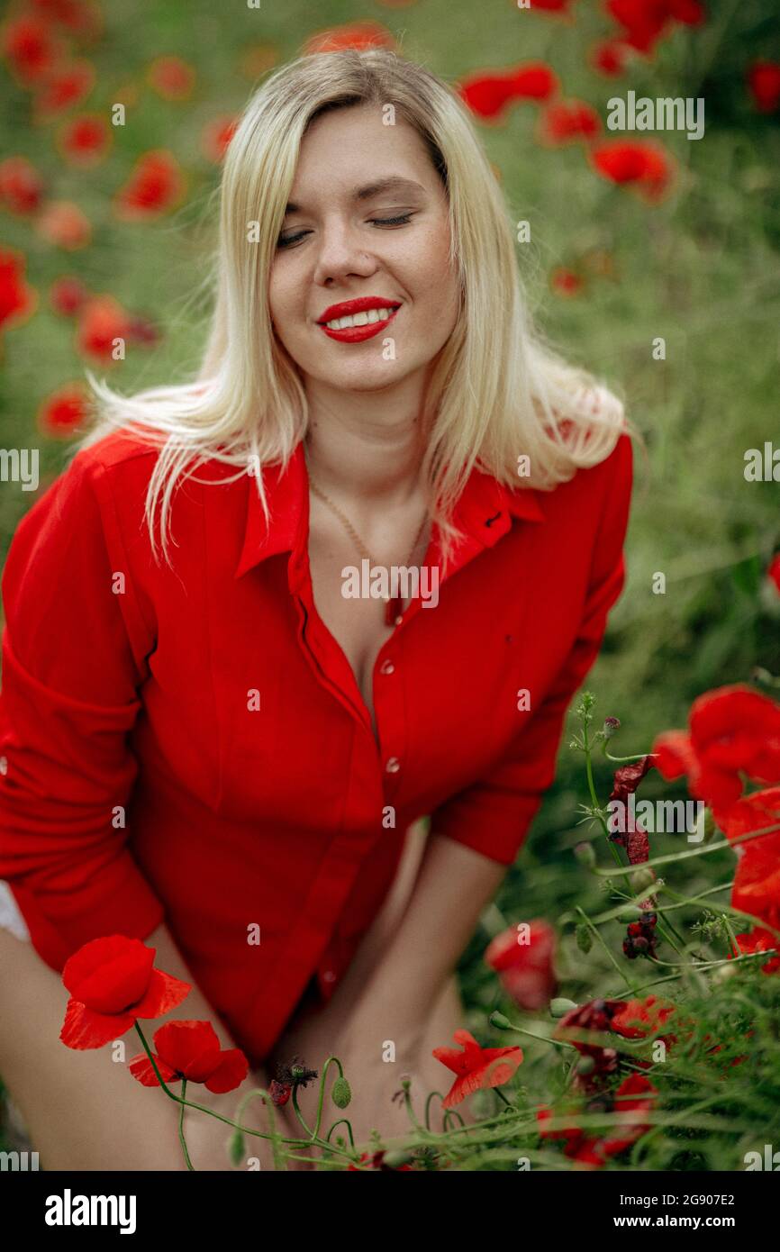 beautiful girl in a field with red poppies in a red shirt Stock Photo ...