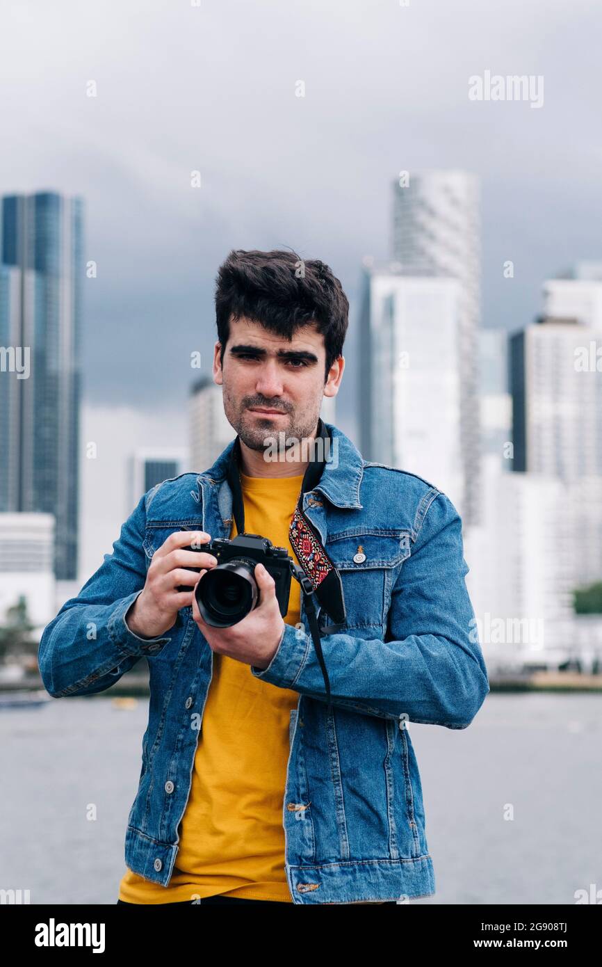 Handsome young man in denim jacket using camera Stock Photo