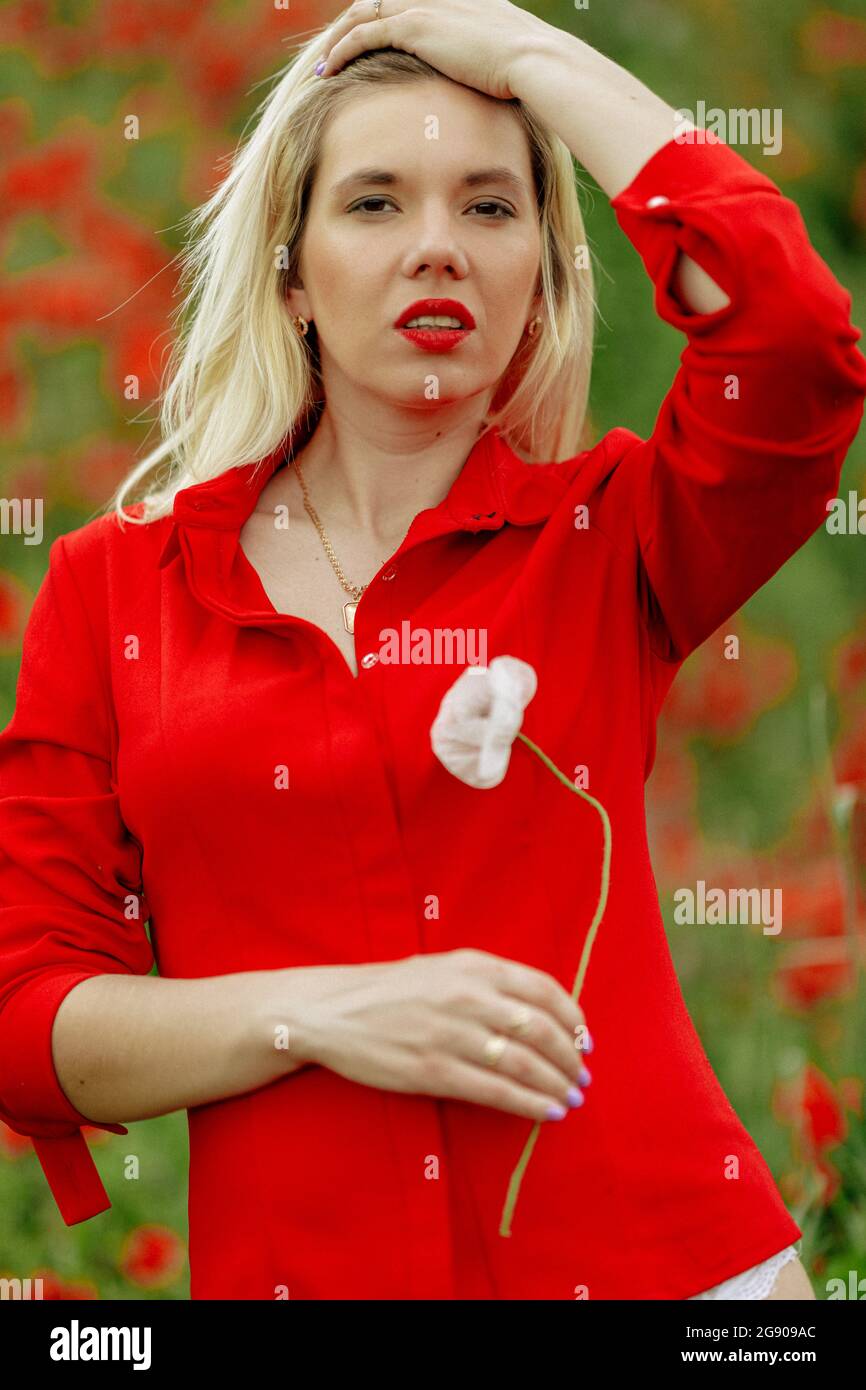 beautiful girl in a field with red poppies in a red shirt Stock Photo