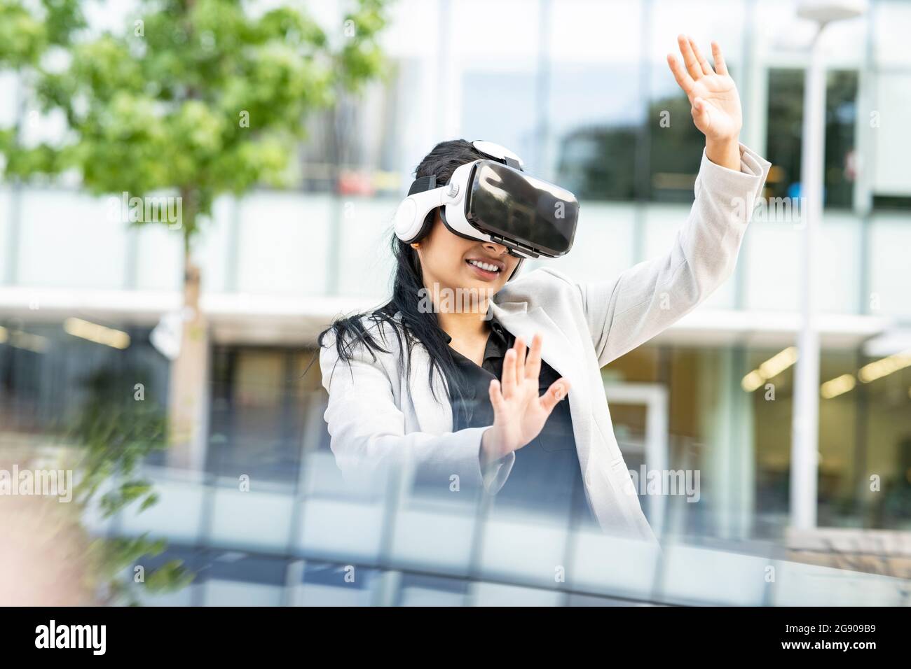 Businesswoman smiling while using virtual reality headset Stock Photo