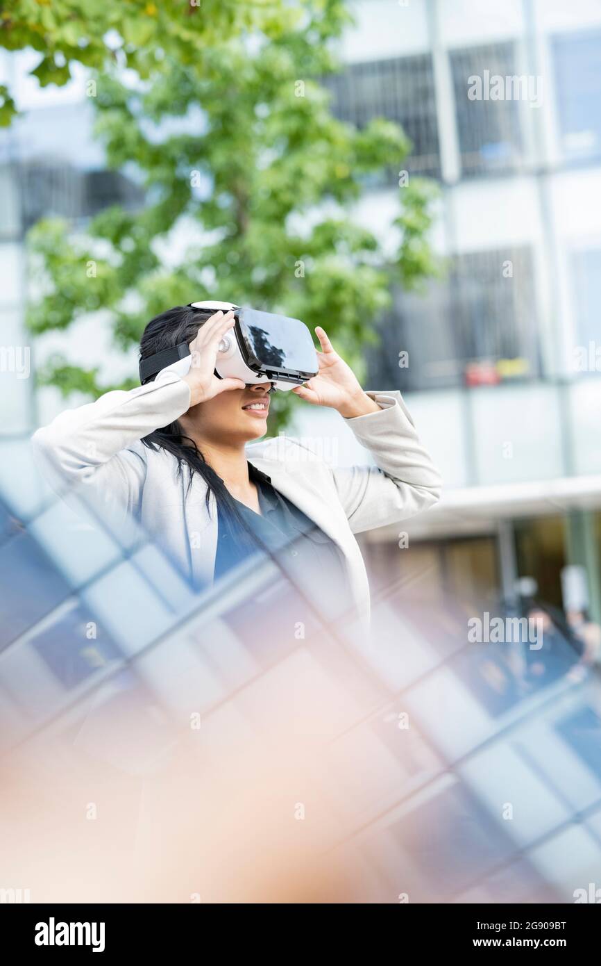 Female professional with hand raised using virtual reality headset Stock Photo