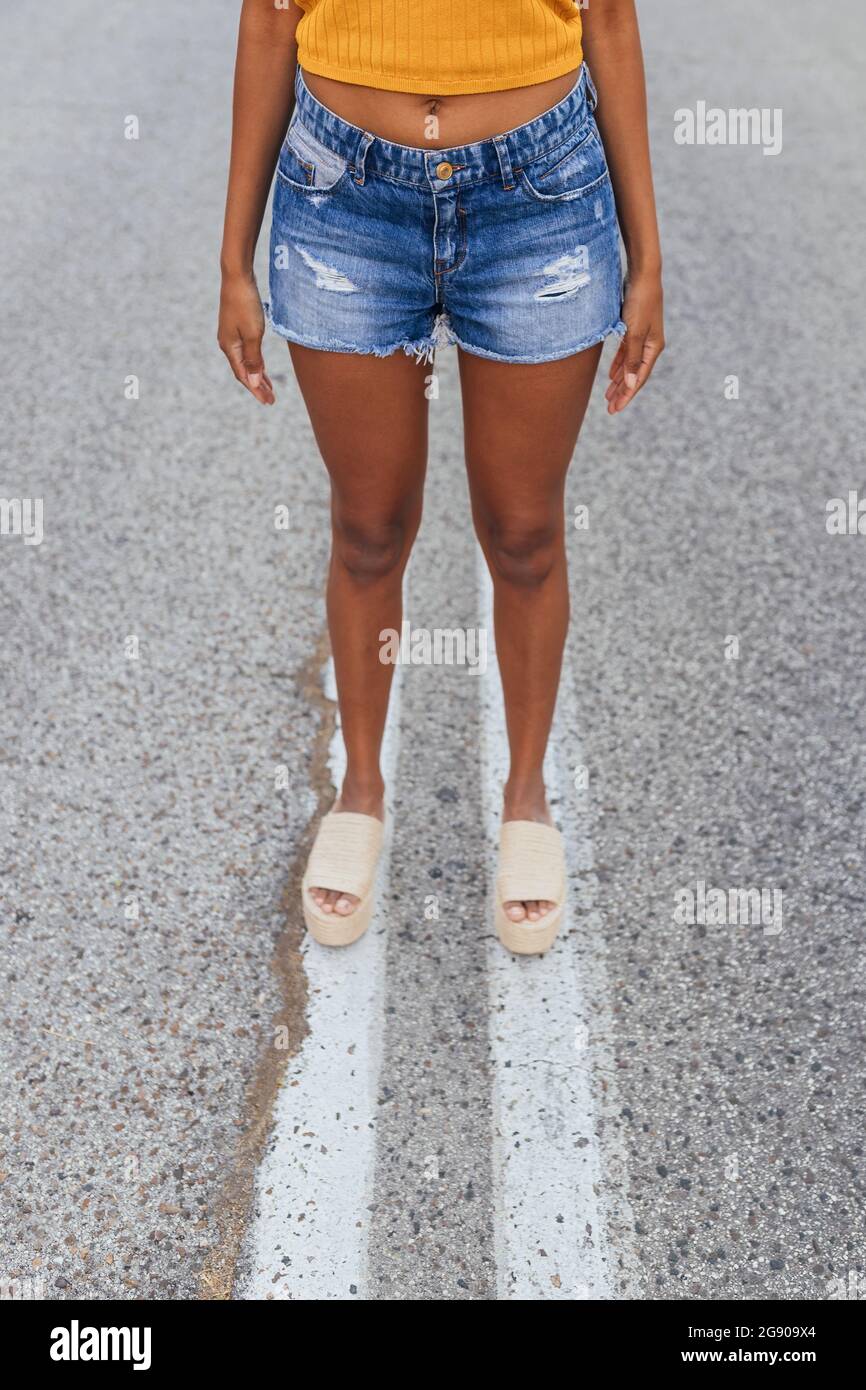 Young woman wearing denim shorts standing on road Stock Photo