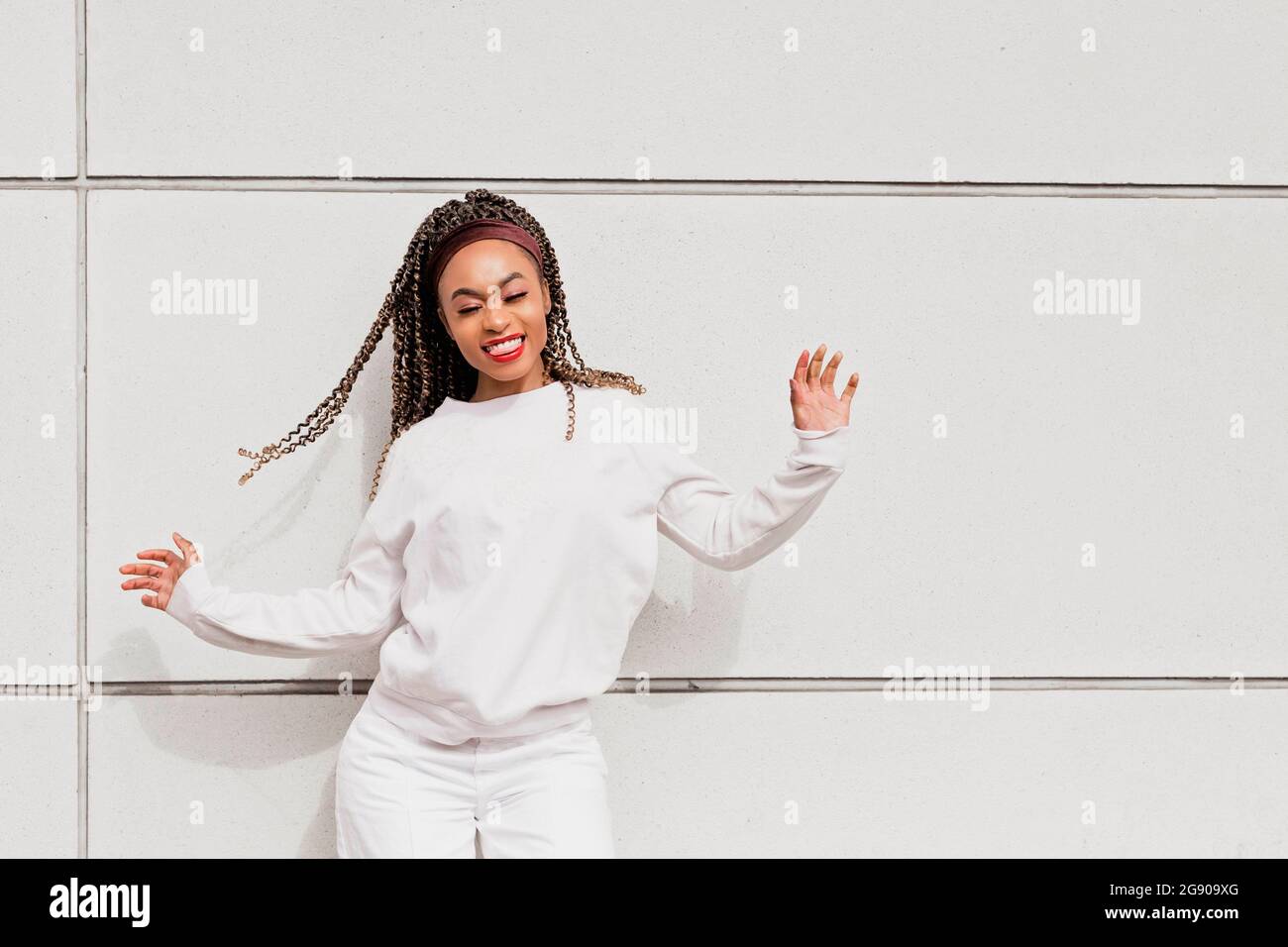 Happy woman with eyes closed dancing in front of white wall Stock Photo Alamy