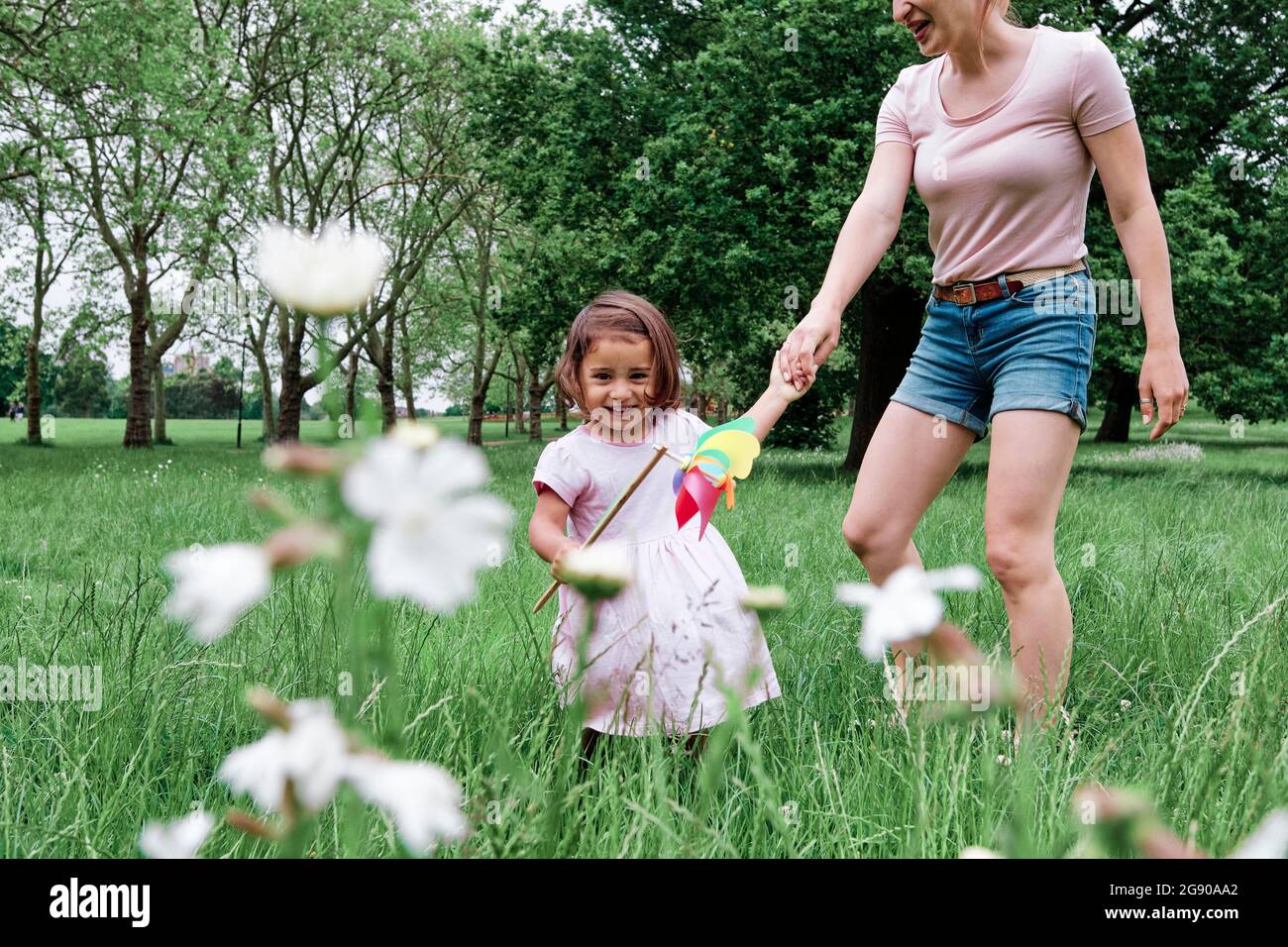 Cute girl holding pinwheel with mother at park Stock Photo - Alamy
