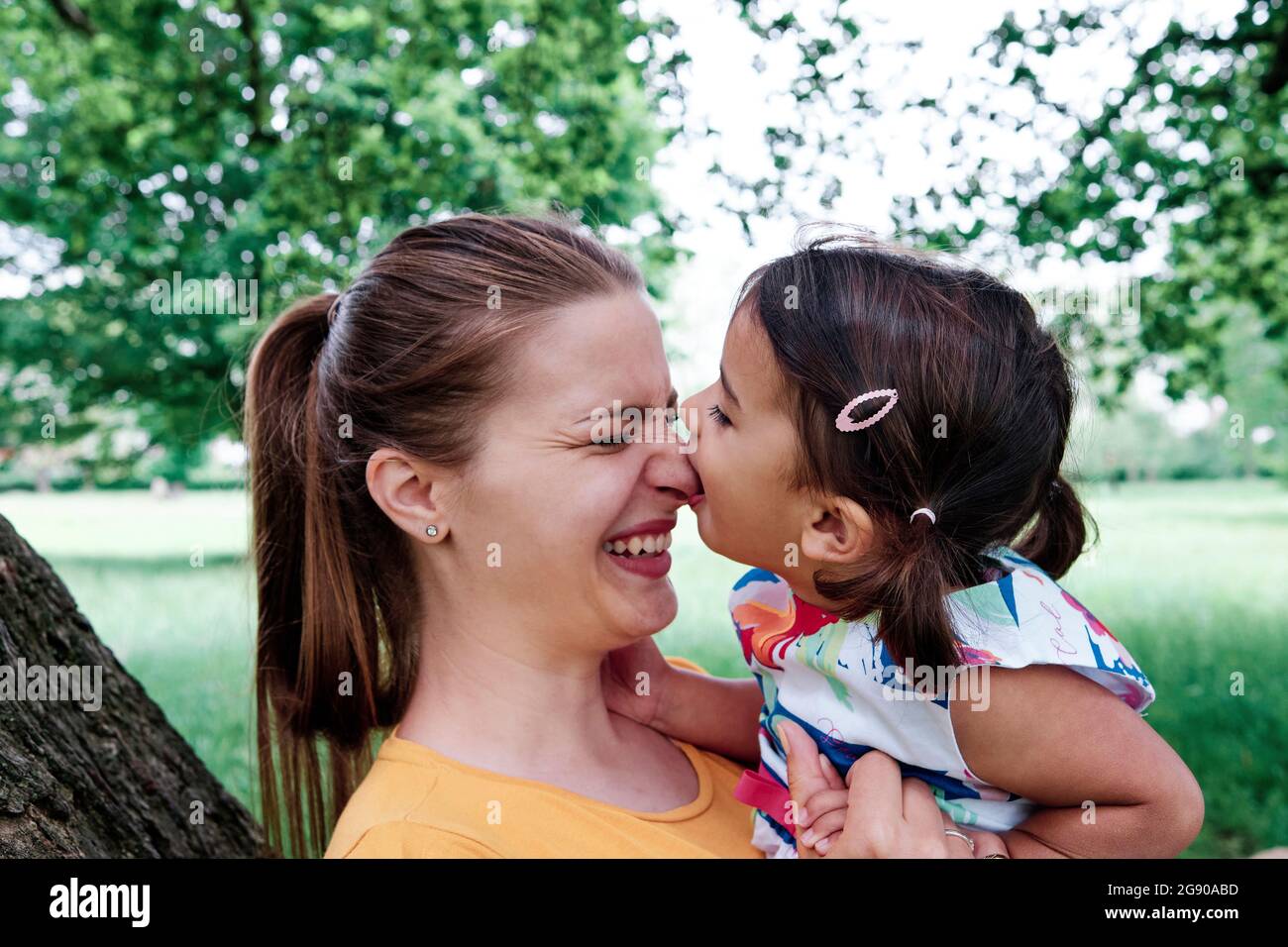 Girl biting mother's nose at park Stock Photo