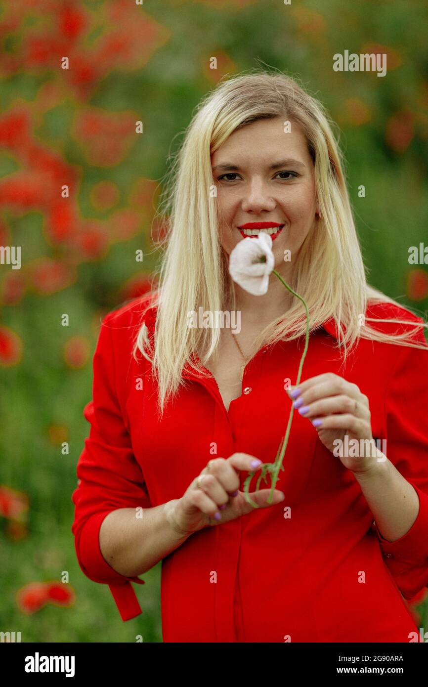 beautiful girl in a field with red poppies in a red shirt Stock Photo ...