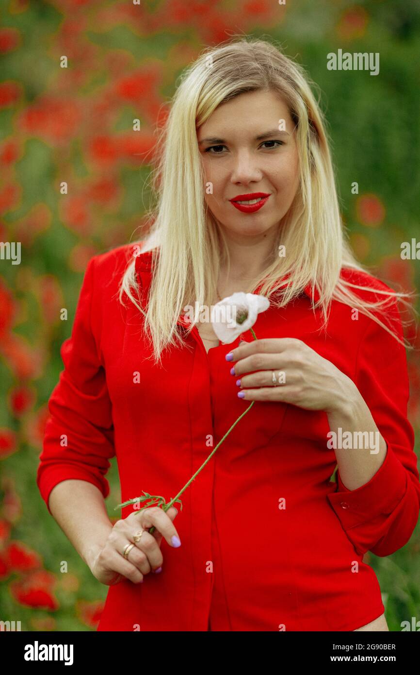beautiful girl in a field with red poppies in a red shirt Stock Photo ...