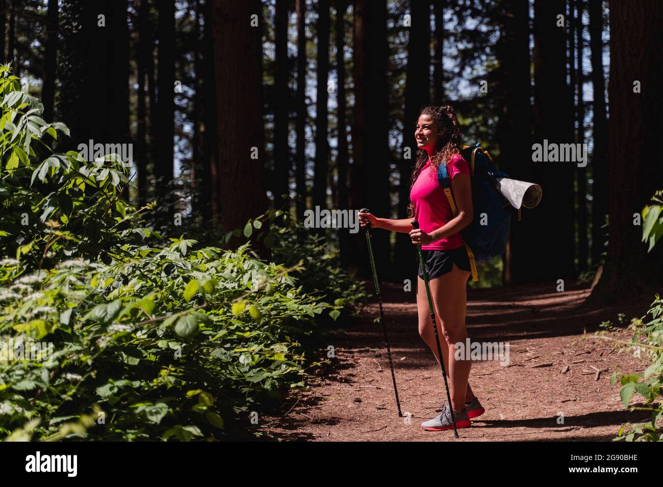 Smiling young woman contemplating while hiking in forest Stock Photo