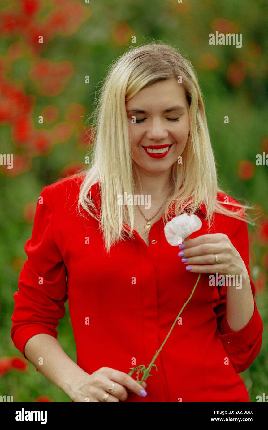 beautiful girl in a field with red poppies in a red shirt Stock Photo ...