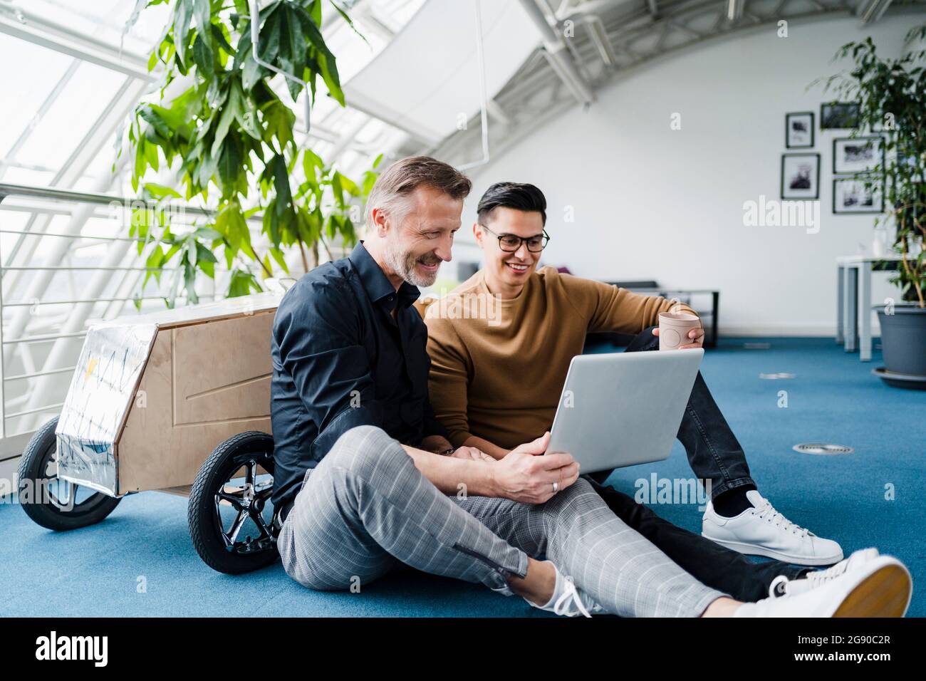 Male colleagues using laptop while sitting in creative office Stock Photo