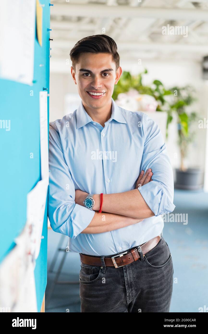 Confident businessman standing with arms crossed in office Stock Photo ...