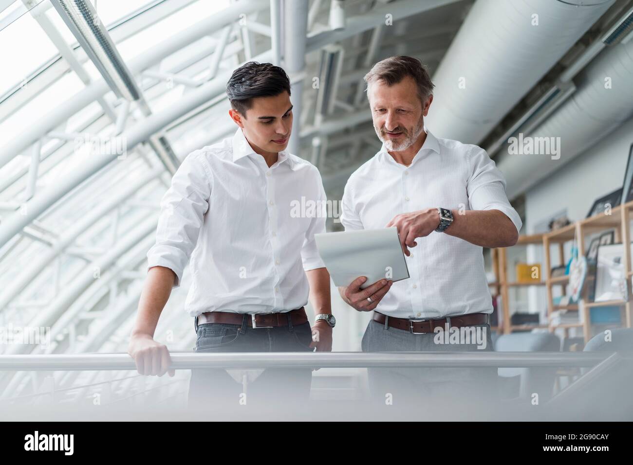 Male professional team reading document while standing in office Stock Photo