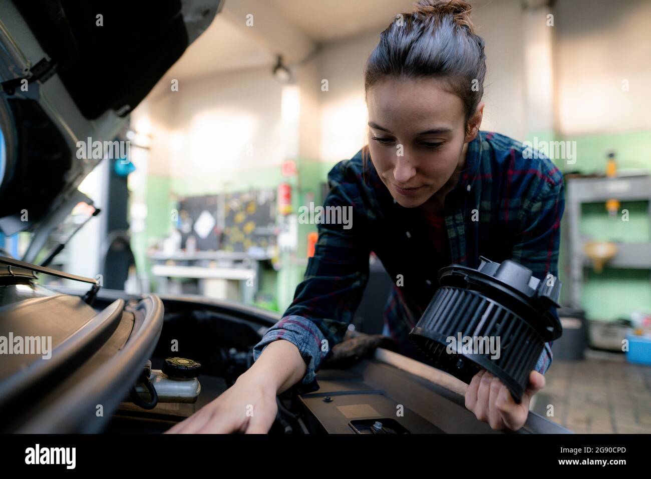 Female mechanic examining car engine at repair shop Stock Photo
