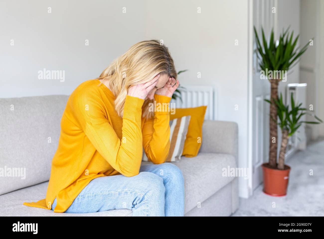 Thoughtful mature woman sitting on sofa at home Stock Photo - Alamy