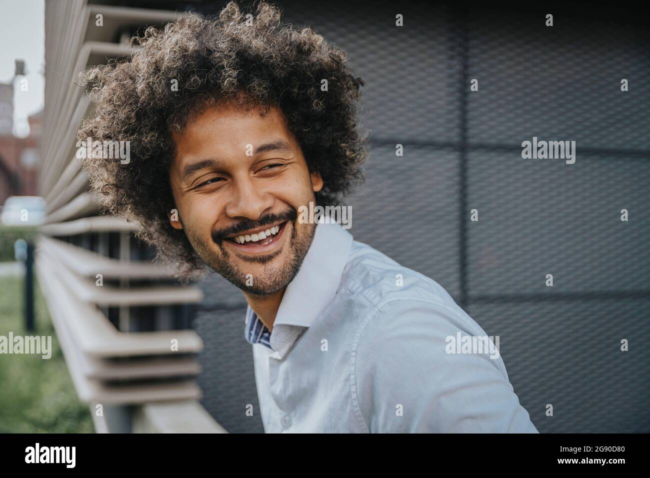 Young man with curly hair looking away while laughing Stock Photo