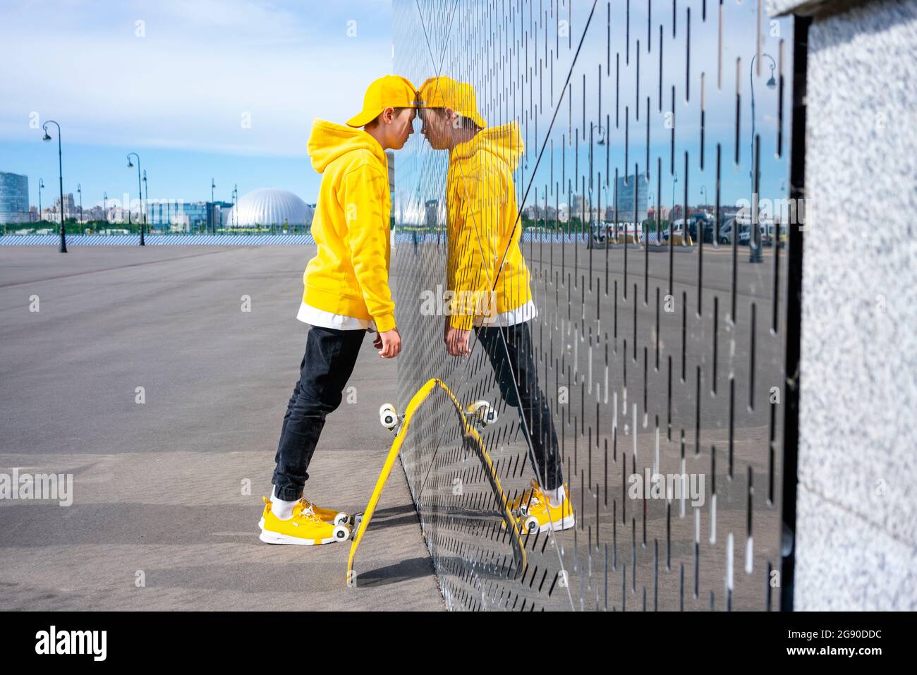 Lonely male skater leaning on metal wall during sunny day Stock Photo