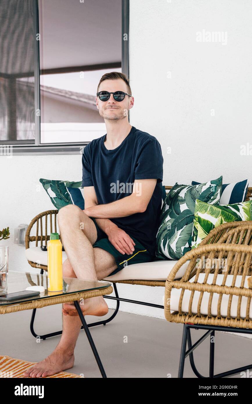 Handsome man sitting on sofa at patio Stock Photo
