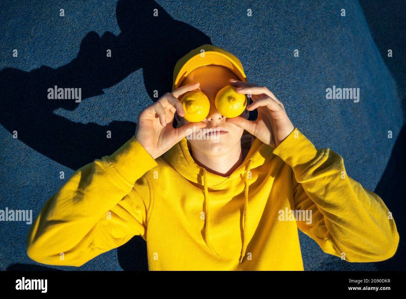 Boy covering eyes with lemons at skateboard park Stock Photo